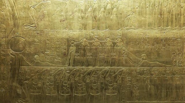 Closeup of golden Tutankhamun shrine panel with goddess and mummified figures relief.