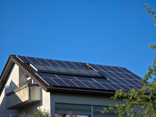 Fototapeta premium house roof fully covered with pv modules representing maximum solar efficiency beneath clear blue sky