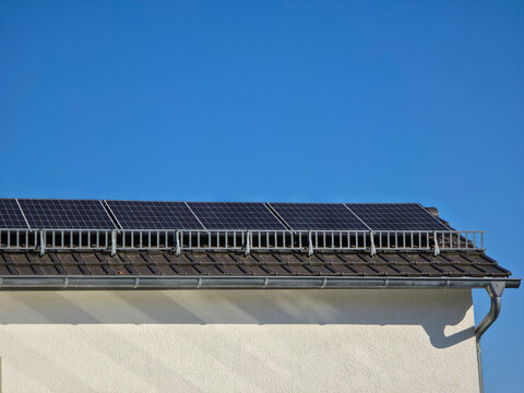 neatly aligned pv modules across house roof highlighting renewable energy success beneath brilliant blue sky