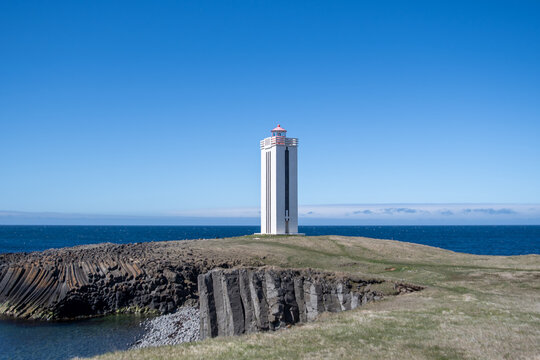a white lighthouse on a beach in Iceland