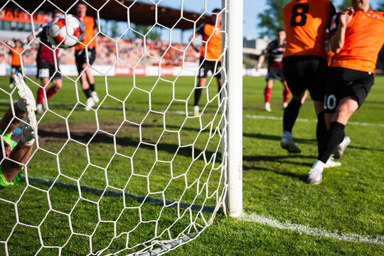 Action on the Soccer Pitch With Players in Motion Seen Through a Stadium Goal Net and Focusing on the net