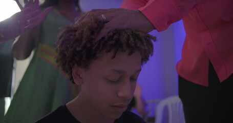 Fototapeta premium Close up of young boy in prayer with eyes closed as man places hand on his head during solemn church blessing ritual