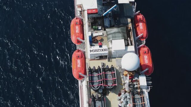 Aerial view of the upper deck of a large ship featuring four red lifeboats and navigation equipment over the deep blue sea near Makunudhoo, Haa Dhaalu Atoll, Maldives.