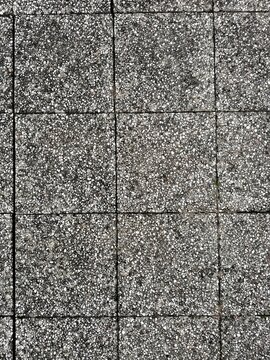 Grey concrete paving slabs with speckled granite aggregate texture