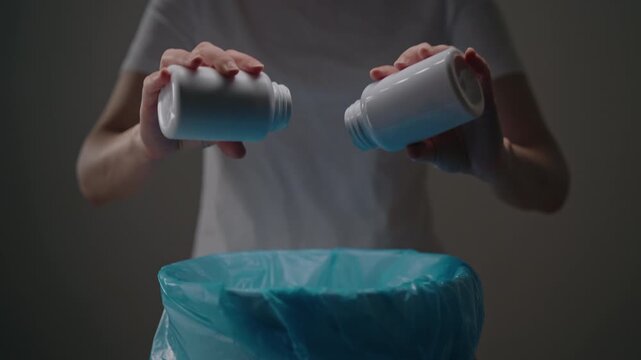 Closeup cropped shot of hands emptying expired prescription medicine from bottles into trash can, concept recovery from addiction, stopping treatment, and proper pharmaceutical waste disposal.