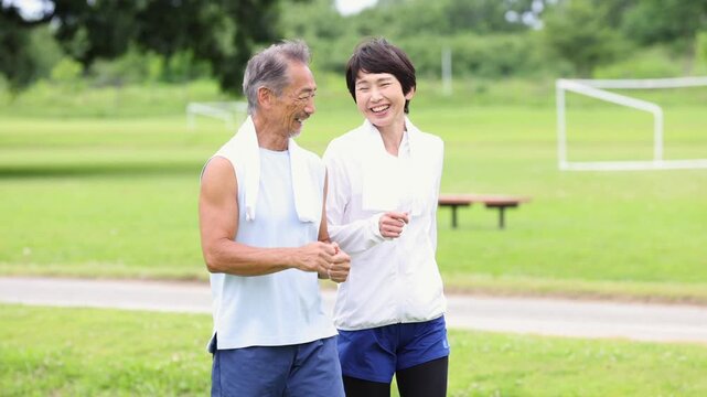 公園でウォーキングを楽しむ笑顔のシニア夫婦