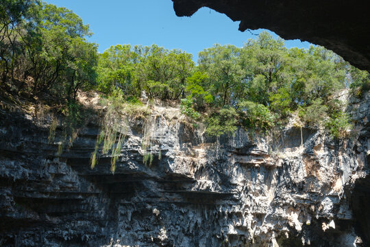 Rock formation with tree tops and clear sky, Melissani Lake