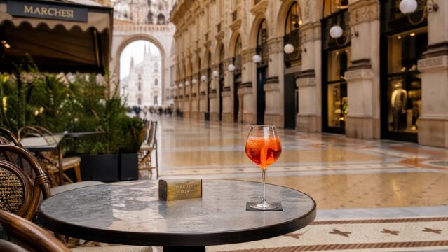 Empty cafe table with a glass at a historic Milanese arcade terrace.