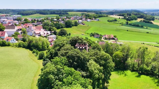 Historischer R&ouml;merturm inmitten eines dichten, gr&uuml;nen Waldst&uuml;cks, umgeben von weiten Feldern und Wiesen in einer idyllischen l&auml;ndlichen Landschaft aus der Vogelperspektive fotografiert.
