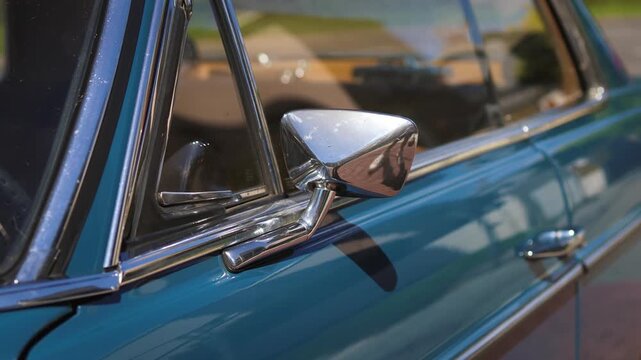 A cinematic close-up shot of a retro cyan car exterior, focusing on the chrome side rearview mirror and shiny details during a road trip.