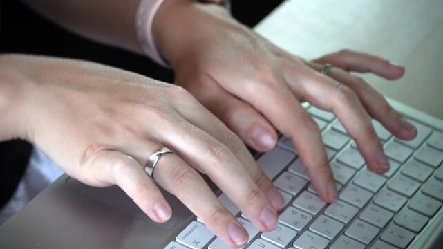 Close-up video of female hands typing on a white laptop keyboard, showing focused work, modern technology, productivity and digital lifestyle concept.