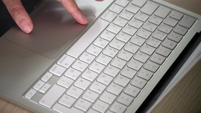 Close-up video of female hands using the touchpad of a white laptop, showing focused work, modern technology, navigation, productivity and digital lifestyle concept.