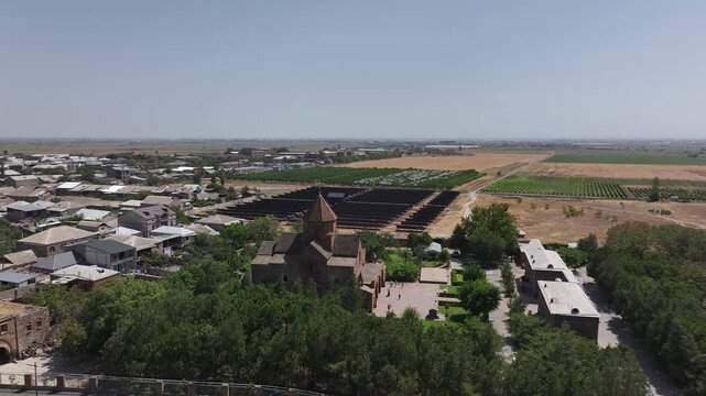An aerial drone shot captures the historic Saint Gayane Church, an ancient Armenian apostolic church showcasing its beautiful stone architecture and green courtyard in the city of Vagharshapat.

