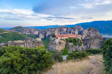 Obraz premium Historic monasteries of Meteora perched atop towering sandstone rock pillars in central Greece. Built by Orthodox monks centuries ago, these remarkable religious structures stand dramatically