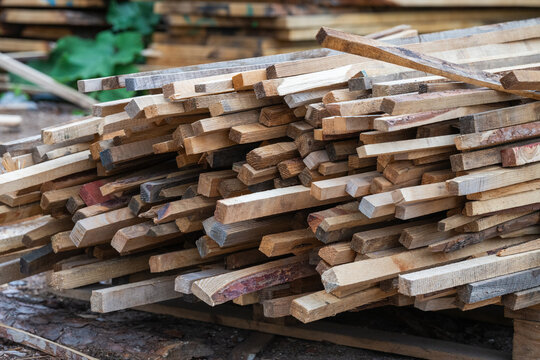 A jumbled pile of small, raw wooden strips and offcuts is stacked on a wooden pallet