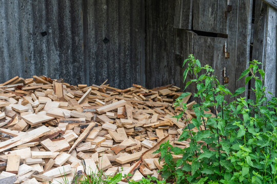 A large pile of small wooden offcuts and scrap pieces is stored inside a rustic wooden barn