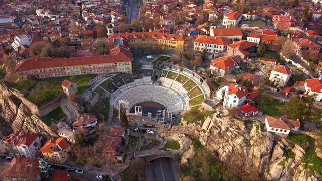 Aerial drone view of the Ancient Roman Theatre of Plovdiv surrounded by historic Old Town architecture, one of Bulgaria's best preserved Roman landmarks and popular cultural tourism destination