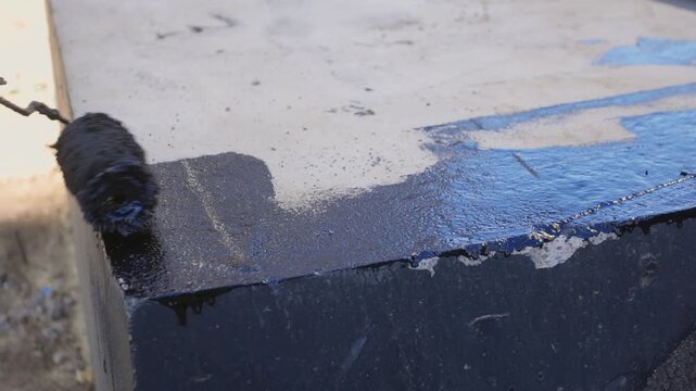 Rooftop concrete slab waterproofing sequence showing roller application progressing from initial
