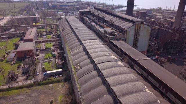 Aerial drone view of a large coal-fired power plant with towering smokestacks, turbine halls, conveyor systems, and industrial infrastructure. Wide overhead perspective of energy generation.