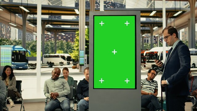 Chroma key screen in busy urban transit hub with diverse passengers waiting for city bus routes and shuttle services with schedule and board.