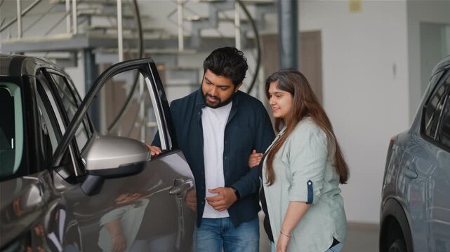 Indian couple choosing new car at dealership showroom