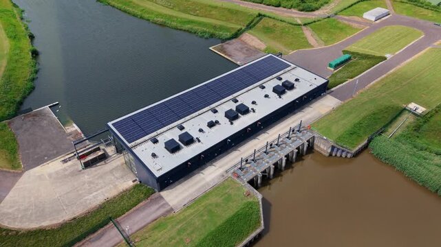 Aerial view of St Germans Pumping Station with solar panels on the roof and sluice gates along the canal in King's Lynn, England, United Kingdom.