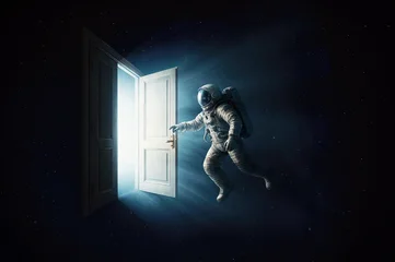 An astronaut in front of an open door to another dimension, from which light emerges. © andrey_l