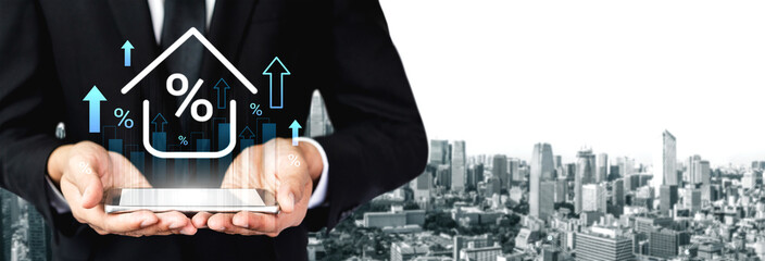 A businessman stands in an urban environment, showcasing a tablet with a house icon and upward arrows, representing the growth of property value and financial success. Gantry © InfiniteFlow