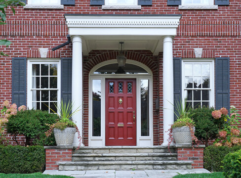 Maroon colored front door of brick house with portico entrance