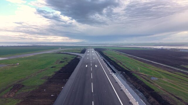 Aerial view straight down an airport runway disappearing into dense fog, with fresh runway markings, threshold stripes and surrounding construction areas creating a dramatic low-visibility aviation sc