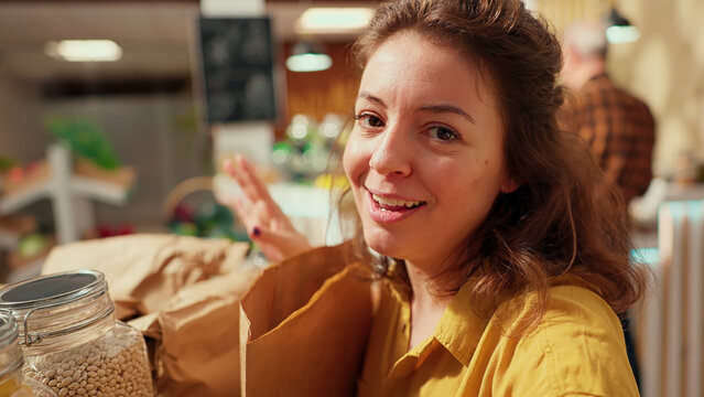 Woman films vlog praising hidden gem eco friendly local neighborhood supermarket, impressed by high quality organic products. Influencer shows around newly opened zero waste store.