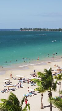 Isla Verde Beach in Puerto Rico. Tourist destination with beach resort and cruise ship tourists, Unrecognizable people enjoying beach summer holiday vacation on caribbean travel. Vertical Video.