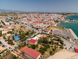 Naklejka premium Nea Moudania marina port, embankment and city, hotels and church in Halkidiki, Greece. Aerial panoramic drone view from above, top view from drone. Summer holidays Europe