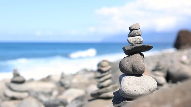 Stacked stone cairns balancing on a sunny peaceful beach