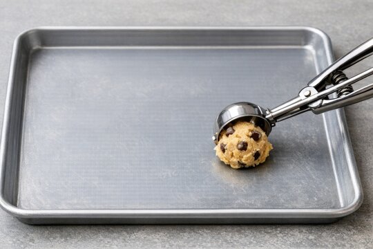 A person scoops cookies from a cookie sheet