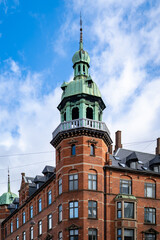 Obraz premium Historic red brick tower with green copper dome against blue sky