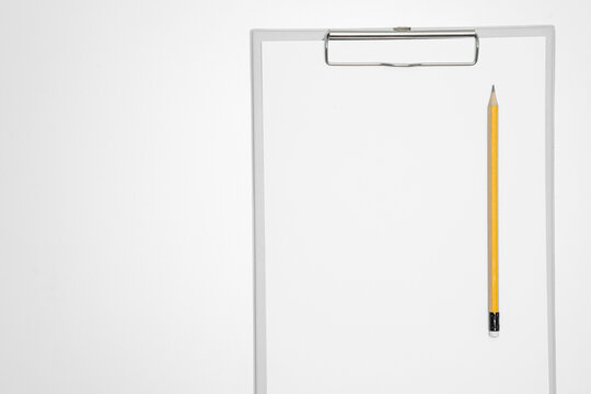 Top view of a blank white paper on a gray clipboard with a yellow pencil isolated on a white background with copy space