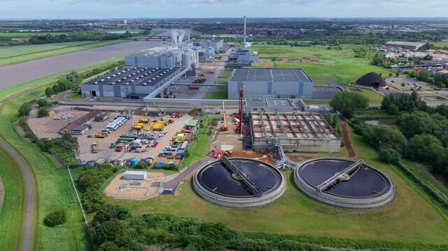 Aerial view of Palm Paper Industrial Factory featuring circular water treatment tanks and large warehouses in King's Lynn, England, United Kingdom.