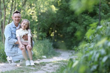 Fototapeta premium Smiling father and his daughter outdoors. Space for text