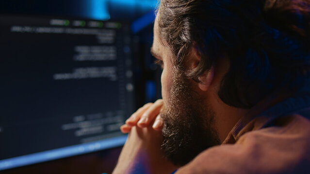 Programmer in home office concentrating on finding bugs while doing coding on computer, extreme close-up shot, iT admin frowning while looking at screen, confused by errors in lines of code.
