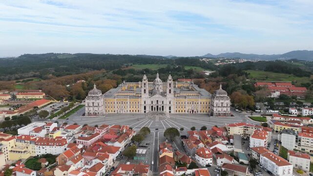 Aerial view of the National Palace of Mafra with its baroque facade, basilica towers and central dome overlooking the town square in Mafra, Lisbon, Portugal.