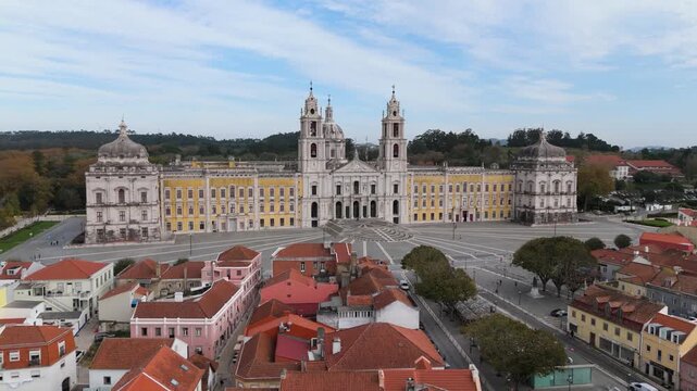 Aerial view of the National Palace of Mafra with its baroque facade and bell towers overlooking the town rooftops in Mafra, Lisbon, Portugal.