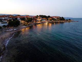Fototapeta premium Aerial top view video of the beautiful town of Nessebar, old church and houses with red tiles, located in the Sunny Beach area of Bulgaria in the evening. Drone view from above