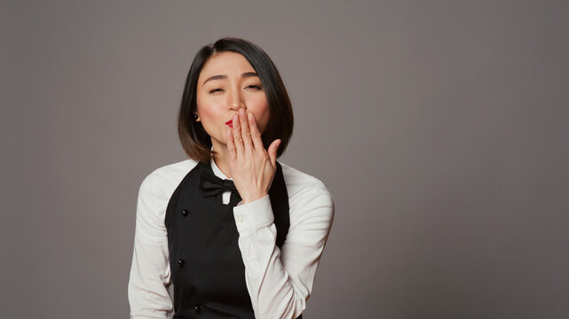 Cute flirty waitress blowing air kisses in front of camera, acting romantic with sweet gesture.