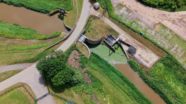 Aerial view of Islington Pumping Station showing the sluice gates and drainage channels surrounded by green fields in King's Lynn, England, United Kingdom.