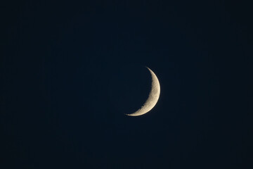 Waxing crescent moon with visible craters in dark night sky © Paul V.