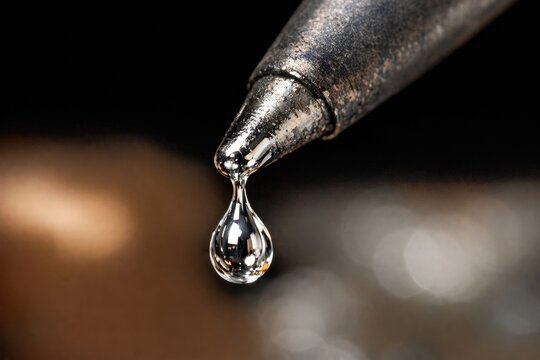A single drop of water falling from a pipe, perfect for representing slow and steady progress or small incremental changes