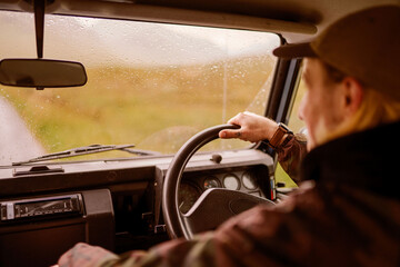 Fototapeta premium Man driving vintage car through rainy countryside