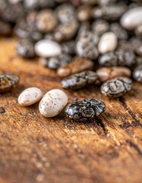 Macro close-up of dark and light chia seeds resting on a textured wooden surface, raw organic superfood, healthy eating ingredients, dietary nutrition.