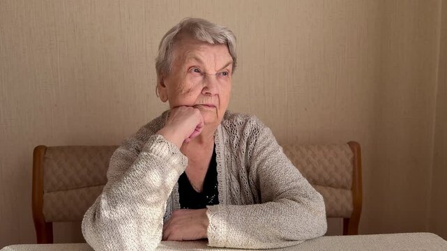 Elderly Caucasian Woman Gazing Thoughtfully Sideways, Propping Chin With Hand Clenched Into Fist, Wearing Knitted Cardigan. Close-up